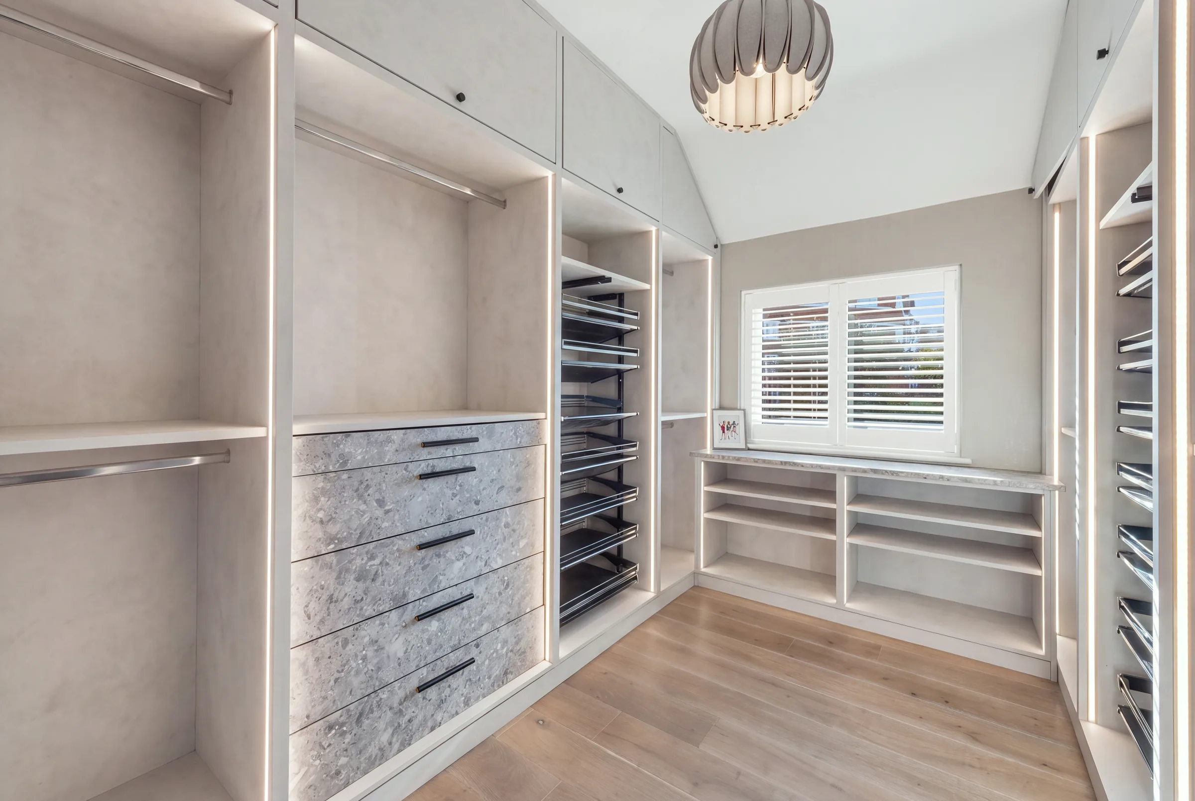 Bespoke walk-in wardrobe with lit hanging rails, drawers and shoe storage