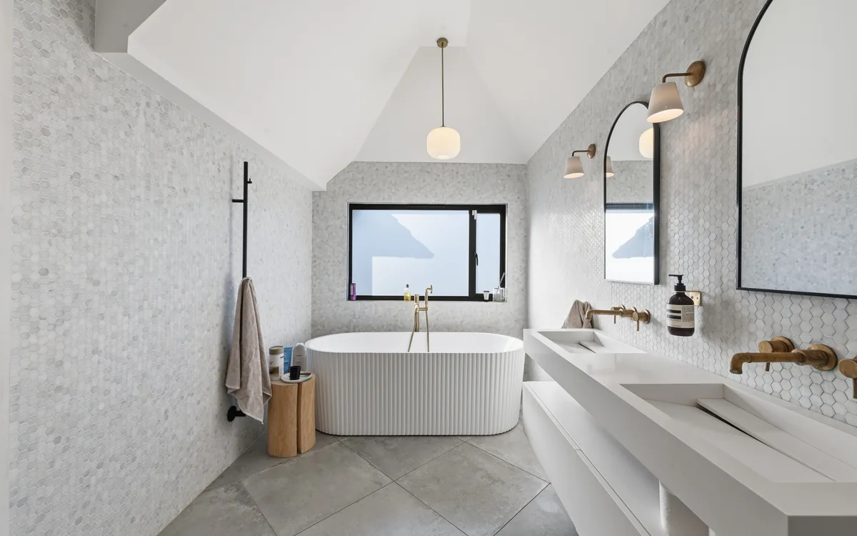 Marble-tiled bathroom with freestanding bath and twin basins