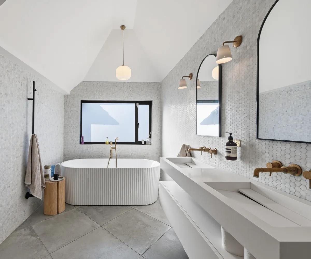 Marble-tiled bathroom with freestanding bath and twin basins