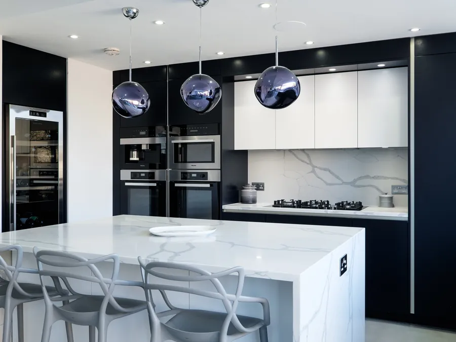 Marble-effect kitchen island with grey bar stools in front of dark tall units and white wall cabinets