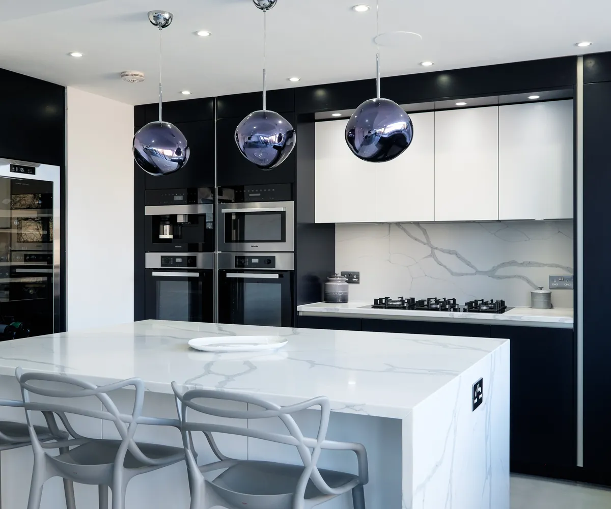 Marble-effect kitchen island with grey bar stools in front of dark tall units and white wall cabinets
